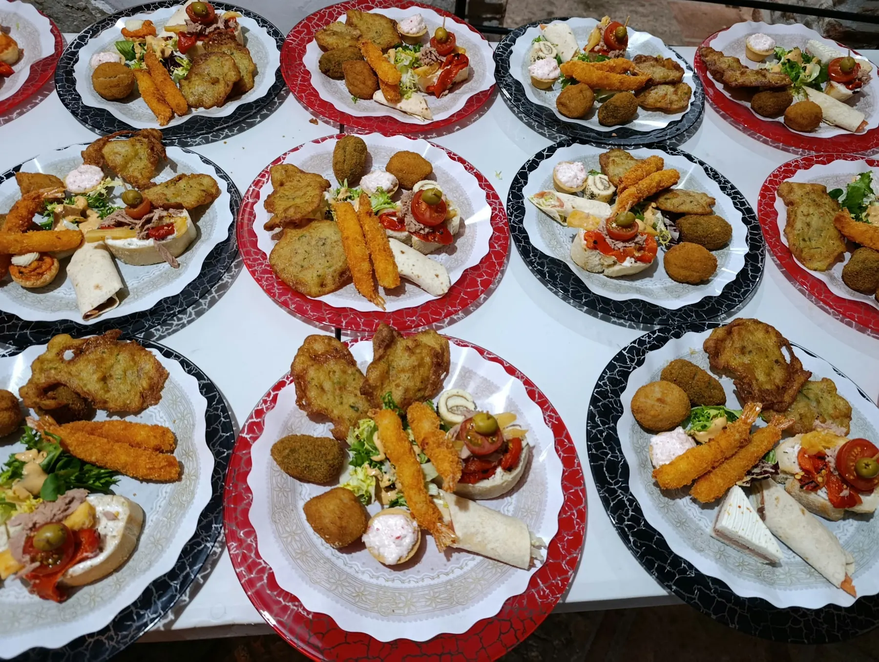 Platos de entrantes servidos para un banquete: croquetas, langostinos rebozados y canapés