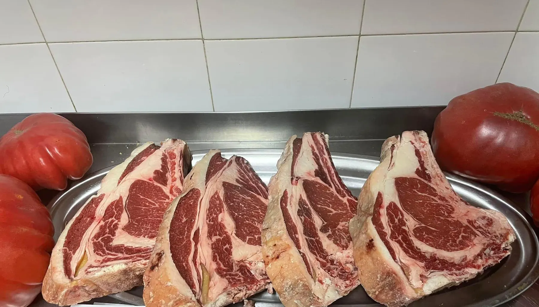 Chuletones de vaca crudos en una bandeja, antes de pasar por la brasa