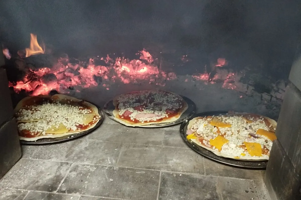 Pizzas dentro del horno de leña, junto a las ascuas