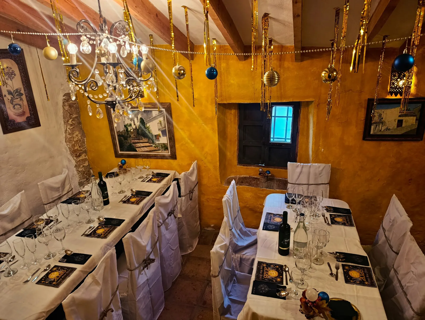 Salón con mesas vestidas de blanco y guirnaldas de Navidad colgadas de las vigas