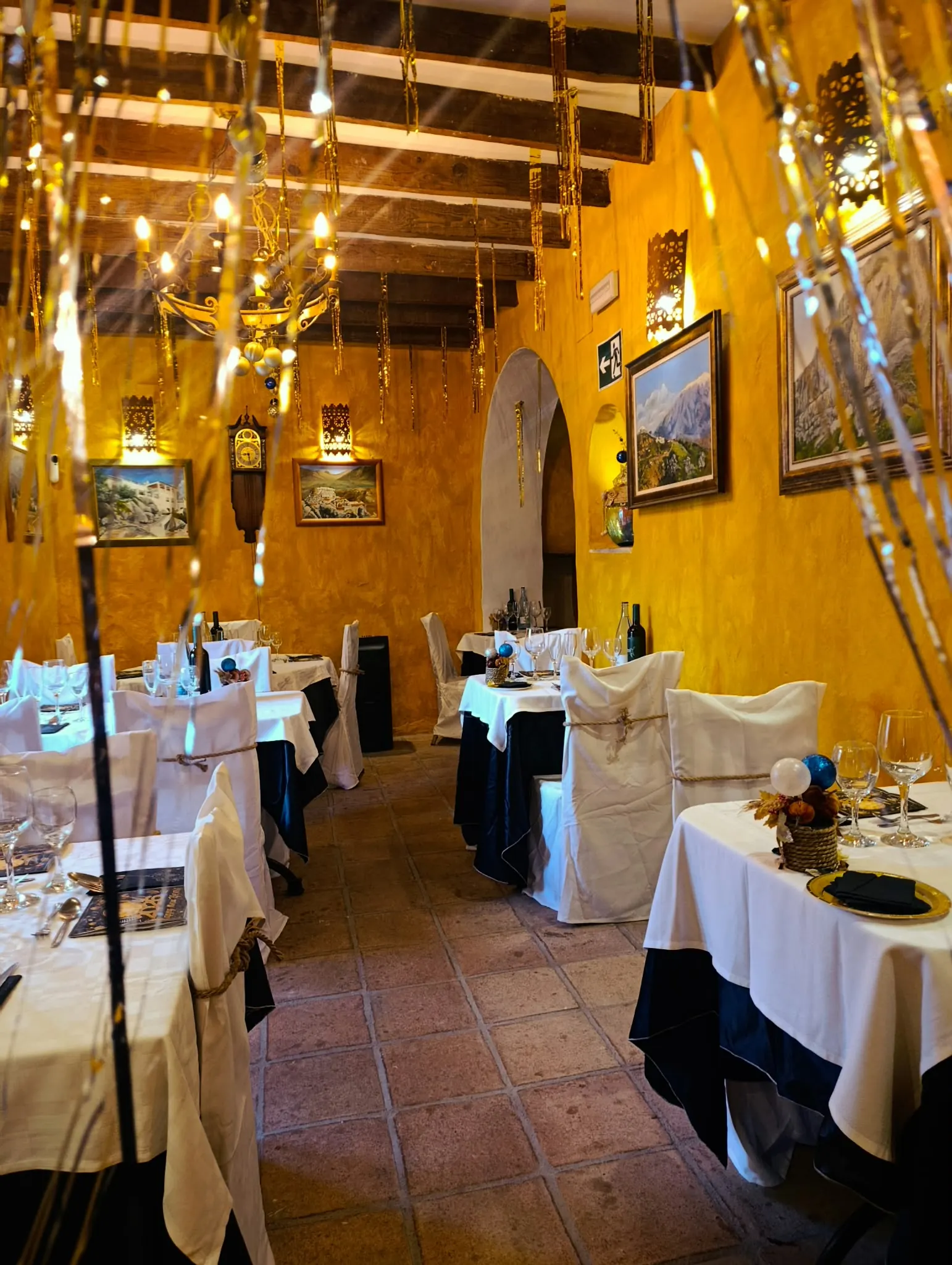 Salón largo montado para la cena de Navidad, con guirnaldas doradas en las vigas