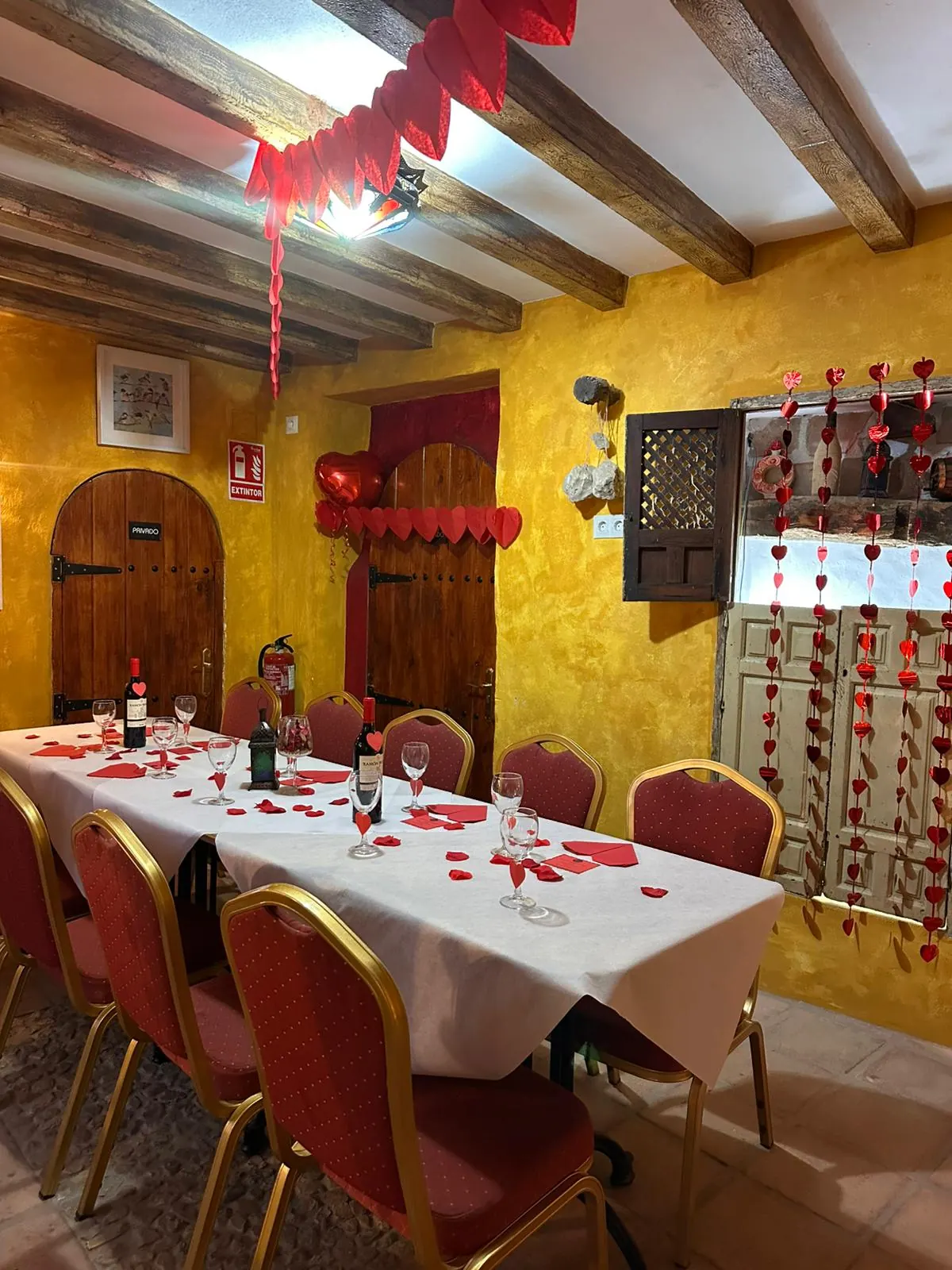 Salón ocre decorado con corazones rojos para San Valentín, con puertas de madera en arco